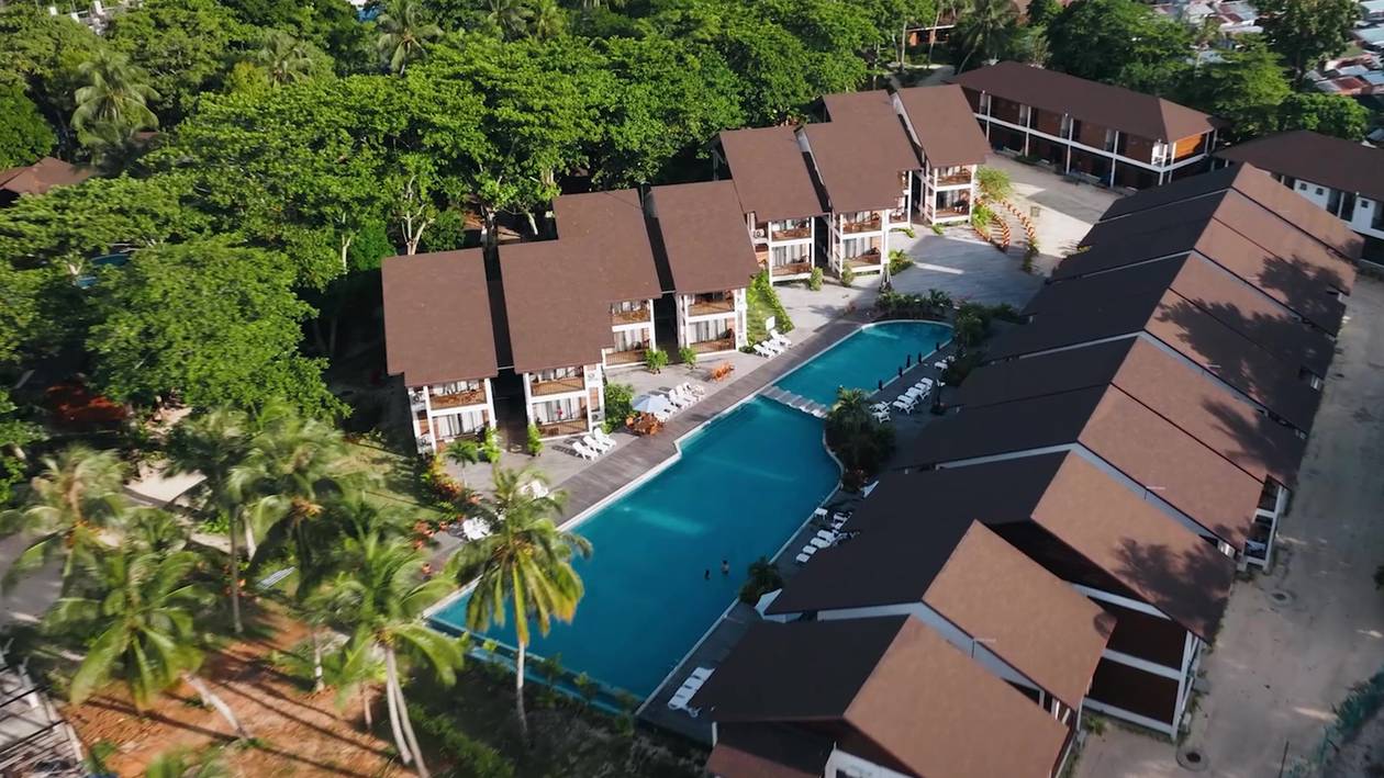 Aerial view of Borneo Divers Mabul Resort: a pool between rows of brown-roofed chalets and trees (placeholder, to recheck when the photo is replaced)