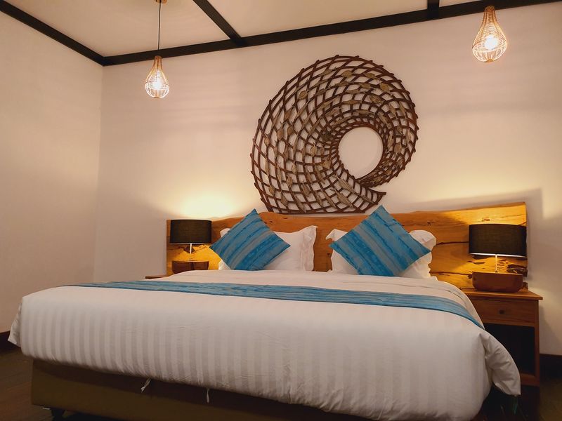 Room with a double bed, blue cushions, bedside lamps and a woven wall ornament at Borneo Divers Mabul Resort (placeholder, to recheck when the photo is replaced)