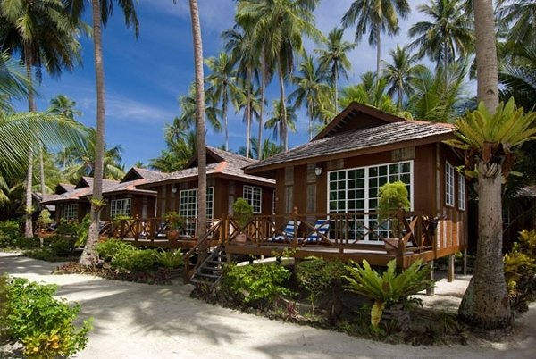 Row of timber chalets with verandahs beside a sand path under tall coconut palms at Sipadan-Mabul Resort (placeholder, to recheck when the photo is replaced)
